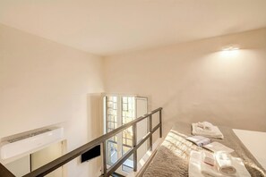 Quarto de hotel com cama, janela, porta e ar condicionado fixado na parede.