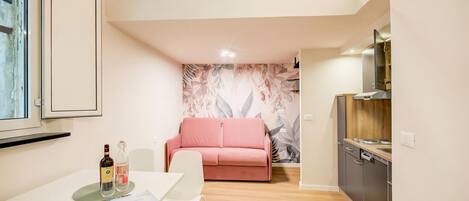 A compact living space with a dining table, a sofa, a kitchenette, and a window.
