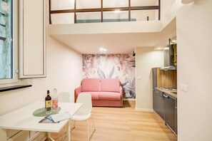 Um espaço compacto com mesa de jantar, sofá, cozinha compacta e janela.