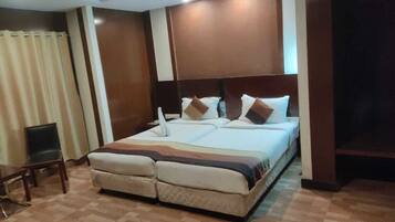 Una habitación de hotel con una cama grande, una silla y un televisor.