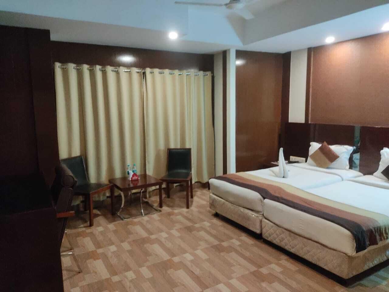 A hotel room with a bed, two chairs, a small table, and a curtain.