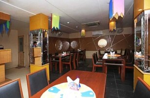 Un restaurante con varias mesas y sillas, un elemento decorativo central en cada mesa y un techo adornado con decoraciones colgantes.