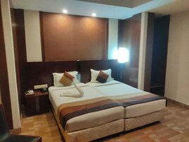 Una habitación de hotel con una cama grande, una mesita de noche y una lámpara de pared.