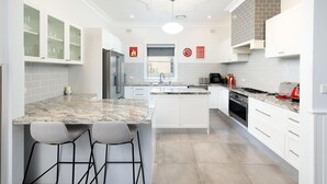 Eine moderne Küche mit weißen Schränken, Granit Arbeitsplatten, einem eingebauten Backofen und einer Küchenrückwand aus Ziegelsteinen.