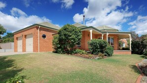 A two-story brick house with a covered porch, a garage, and a well-maintained lawn.