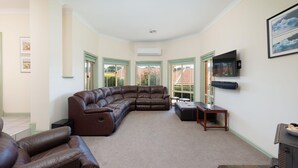 A living room with a sectional sofa, a fireplace, and a television mounted on the wall.