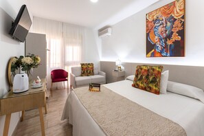 A hotel room with a bed, a desk with a kettle, a chair, a TV, and a painting on the wall. - URBAN ROOMS B&R  (Málaga)