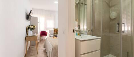 A modern bathroom with a glass shower enclosure, a white vanity, and a wooden floor.