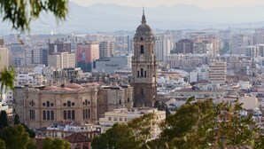 A cityscape with a prominent historical building featuring a dome and bell tower, surrounded by modern buildings. - URBAN ROOMS B&R (Málaga)