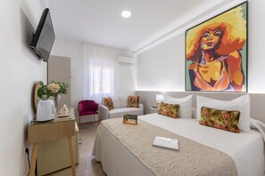 A hotel room with a bed, a desk with a kettle, a chair, a TV, and a painting on the wall. - URBAN ROOMS B&R  (Málaga)