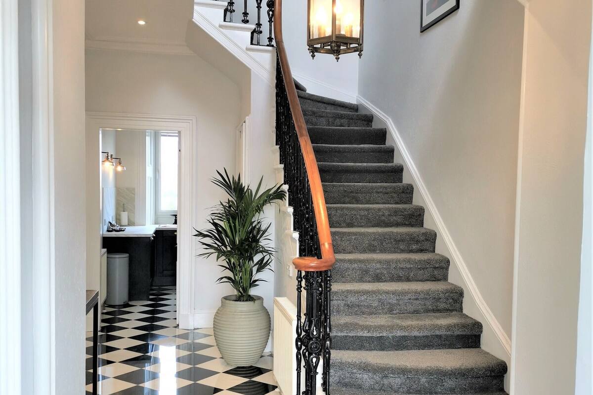 A staircase with a black and white checkered floor, a white door, and a potted plant.
