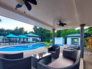 A covered outdoor area with a swimming pool, lounge chairs, and umbrellas. - Cabana Republic (Puerto Princesa)