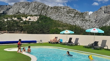 Una piscina al aire libre de temporada, sombrillas, tumbonas