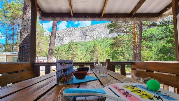 Eine Holzterrasse mit Tisch, Speisekarte und Blick auf eine Berglandschaft.