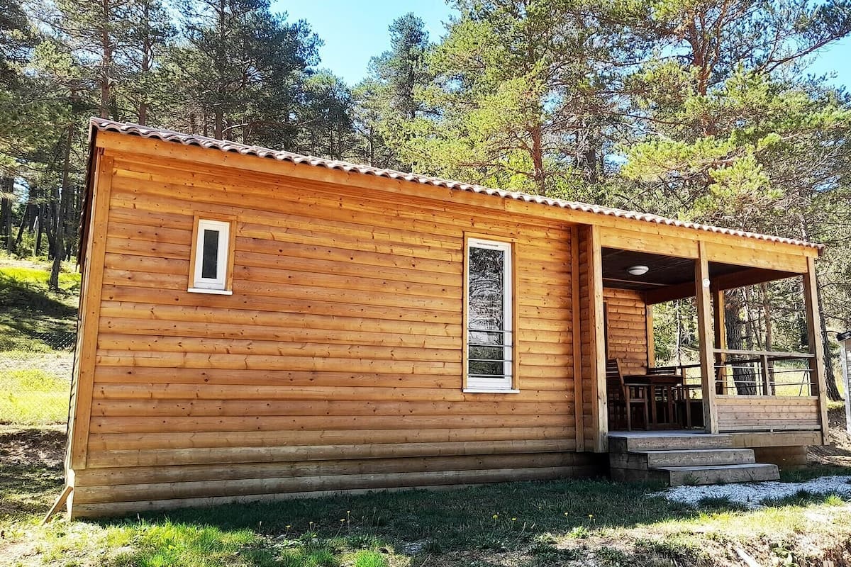A small wooden cabin with a porch, a window, and a door.