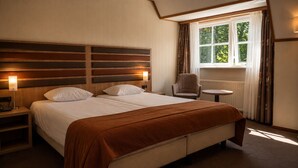 Une chambre d’hôtel avec un lit double, des lampes de chevet, une chaise, une table ronde et une fenêtre avec des rideaux.