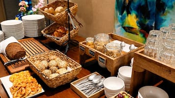 A buffet table with various food items, including bread, pastries, and fruits.