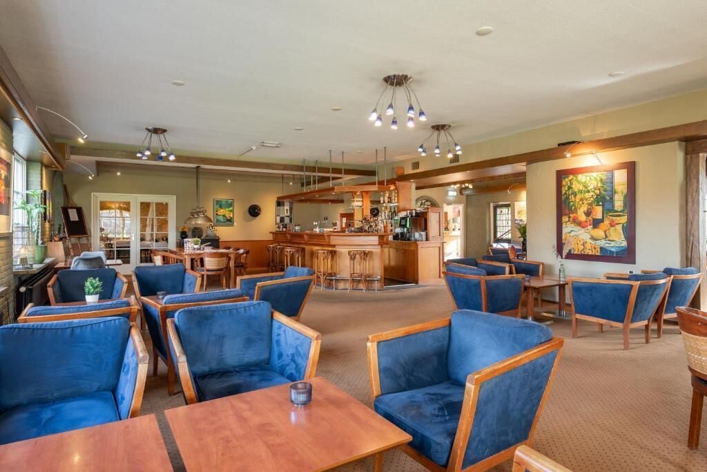 A hotel lobby with seating areas, a bar, and a kitchen in the background.