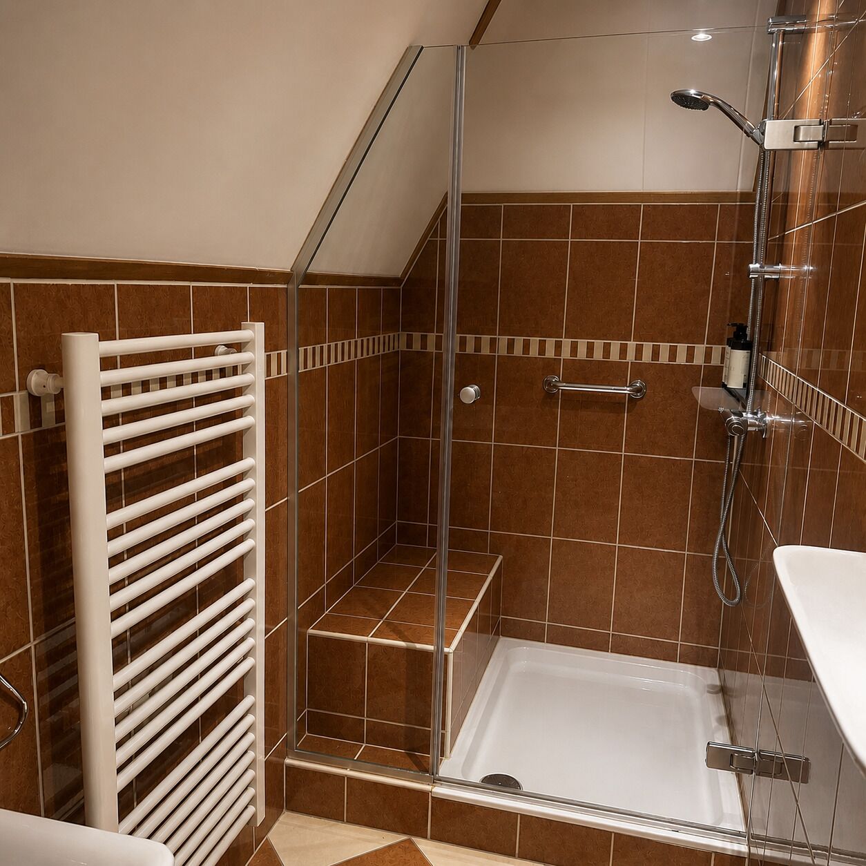 Ducha con cerramiento de vidrio, bañera blanca y un perchero.