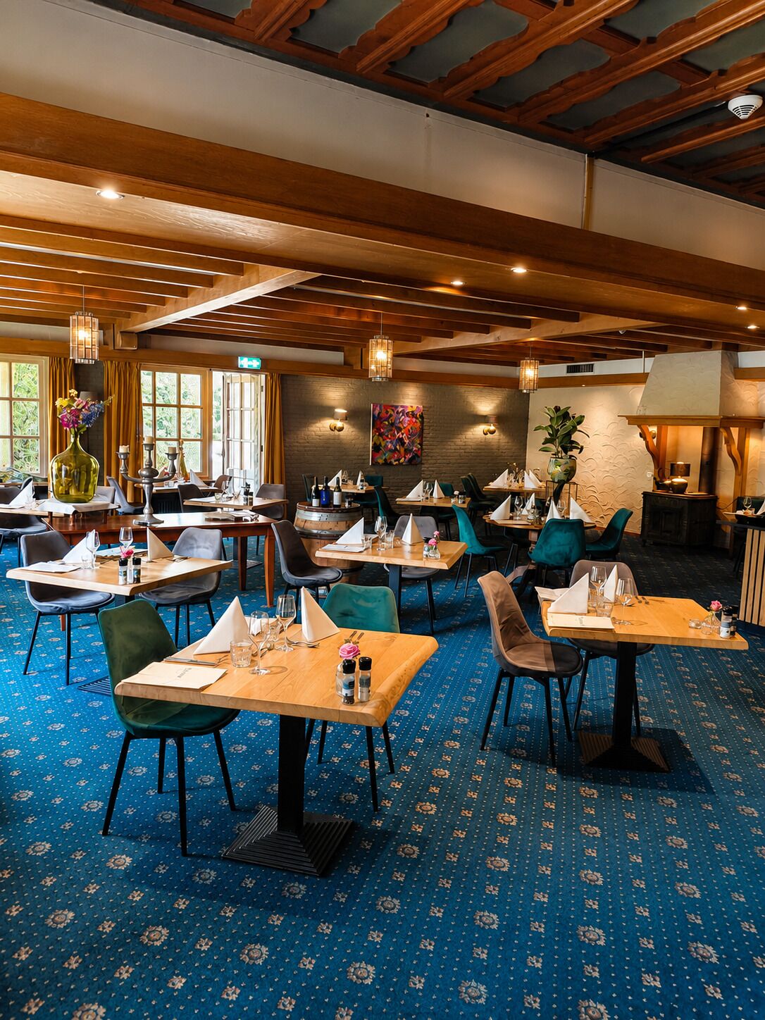 Un restaurant doté de nombreuses tables, de chaises et d’un tapis à motifs.
