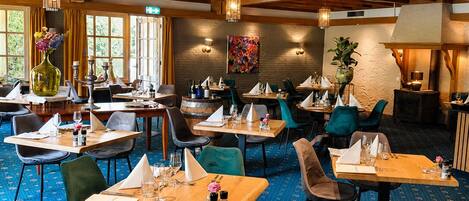 Un restaurante con varias mesas, sillas y una alfombra estampada.