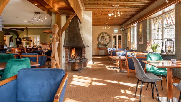 A cozy restaurant with a brick fireplace, wooden beams, and comfortable seating.