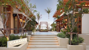A hotel entrance with a sign reading "CABANAS KOH SAMUI," a staircase leading to the lobby, and a view of the surrounding buildings. - Marasca Samui - Small Luxury Hotels of the World (Koh Samui)
