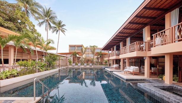 A resort pool area with clear blue water, palm trees, and lounge chairs. - Marasca Samui - Small Luxury Hotels of the World (Koh Samui)