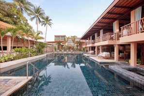 A resort pool area with clear blue water, palm trees, and lounge chairs. - Marasca Samui - Small Luxury Hotels of the World (Koh Samui)