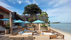 A beachfront lounge with outdoor seating, umbrellas, and a view of the sea. - Marasca Samui - Small Luxury Hotels of the World (Koh Samui)