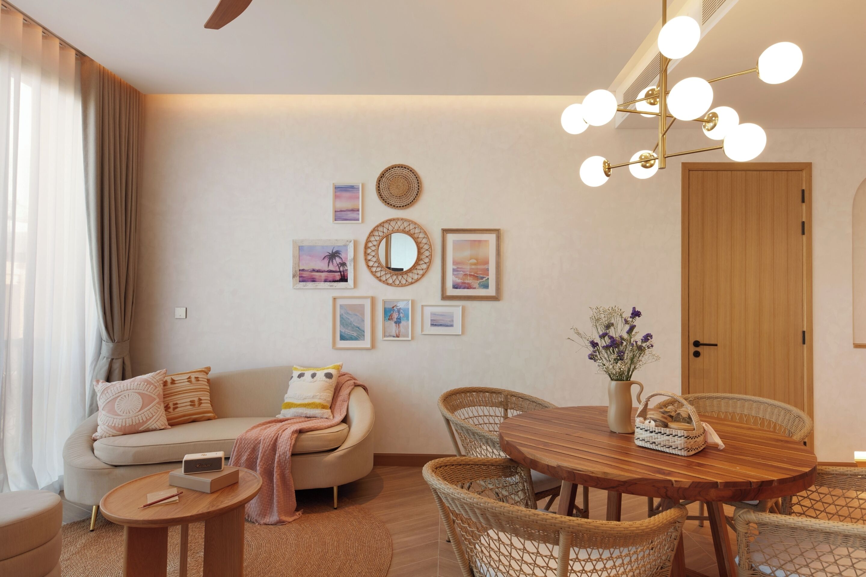 A modern living room with a sofa, a round wooden dining table, wicker chairs, and a ceiling light fixture.