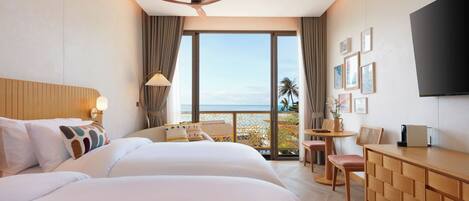 A hotel room with a large bed, a desk, a chair, a TV, and a balcony with a view of the ocean.