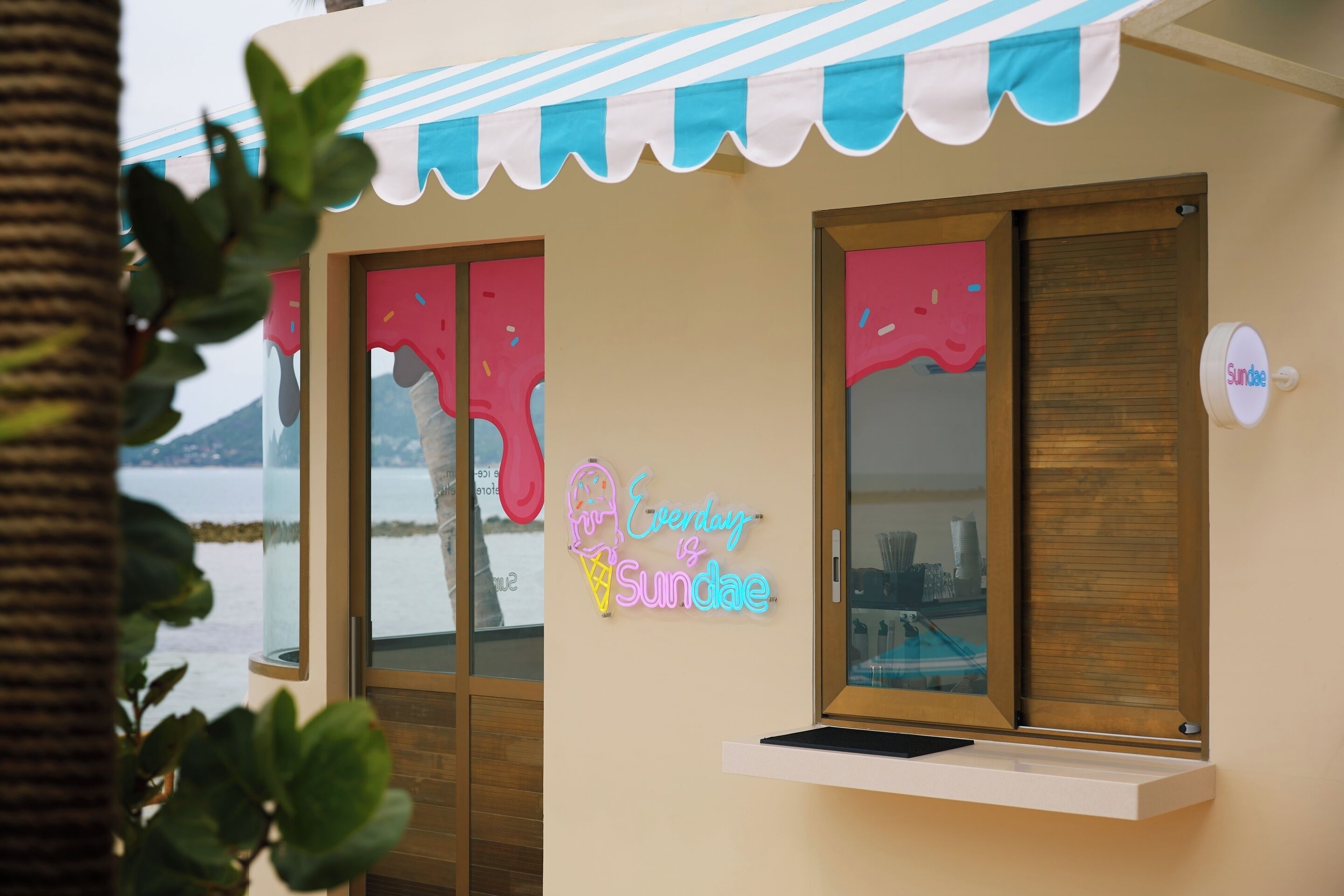 Un edificio con un letrero de neón que dice 'Everyday is Sundae' y vista al mar.