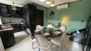 Ett modernt kök med svarta skåp, ett matbord med plats för fyra personer och en grön accentvägg.