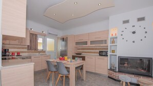 Une cuisine moderne avec des meubles en bois, une table à manger avec des chaises, un four à micro-ondes encastré et une cheminée.
