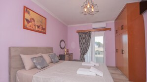 Une chambre à coucher avec un grand lit, une table de chevet, une commode et un tableau au mur.