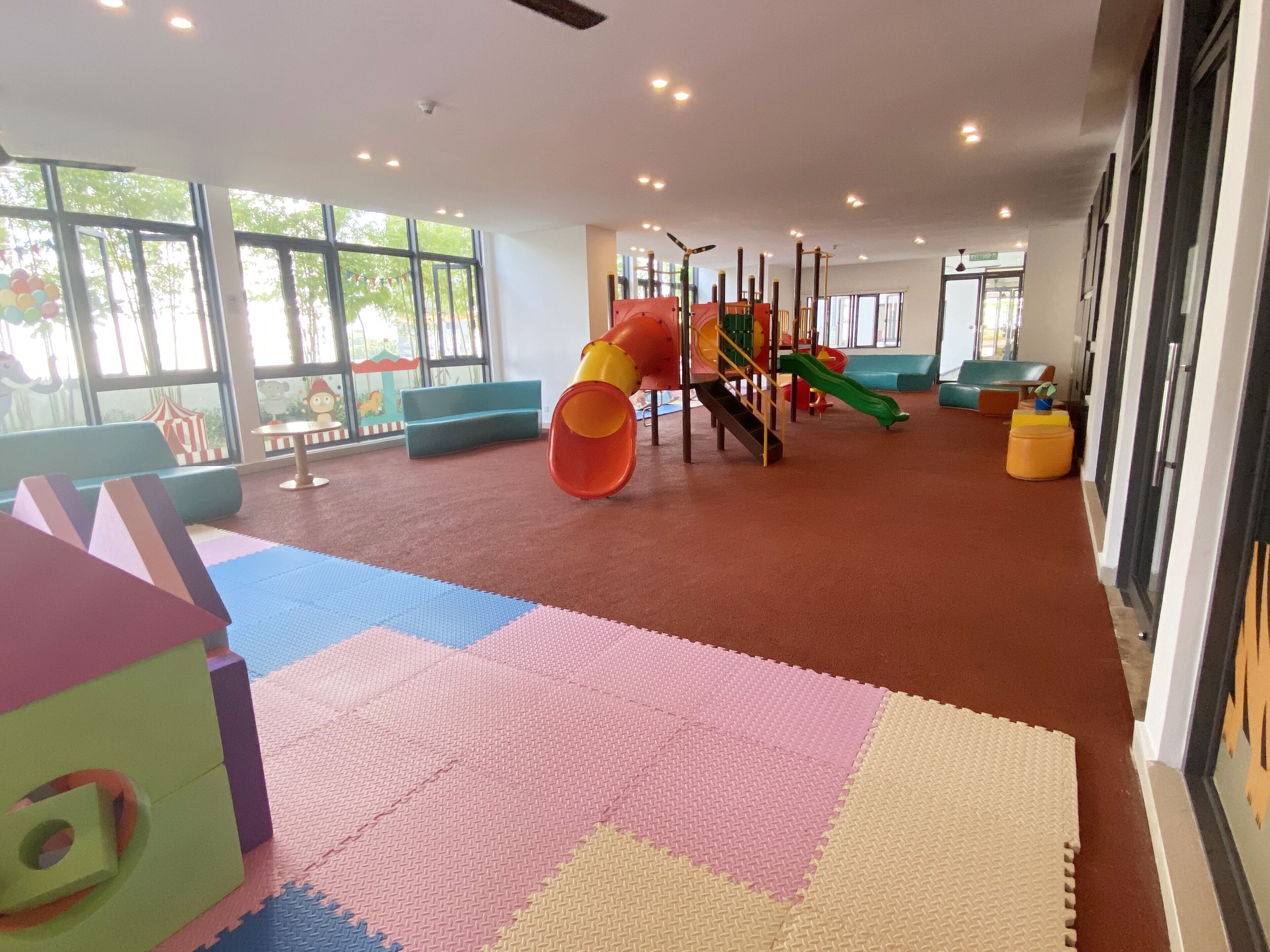 A children's play area with a slide, climbing structures, and colorful mats.