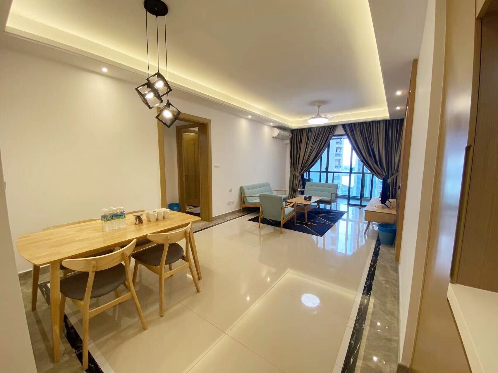 A modern living room with a dining area, featuring a wooden table and chairs, a sofa, and a coffee table.
