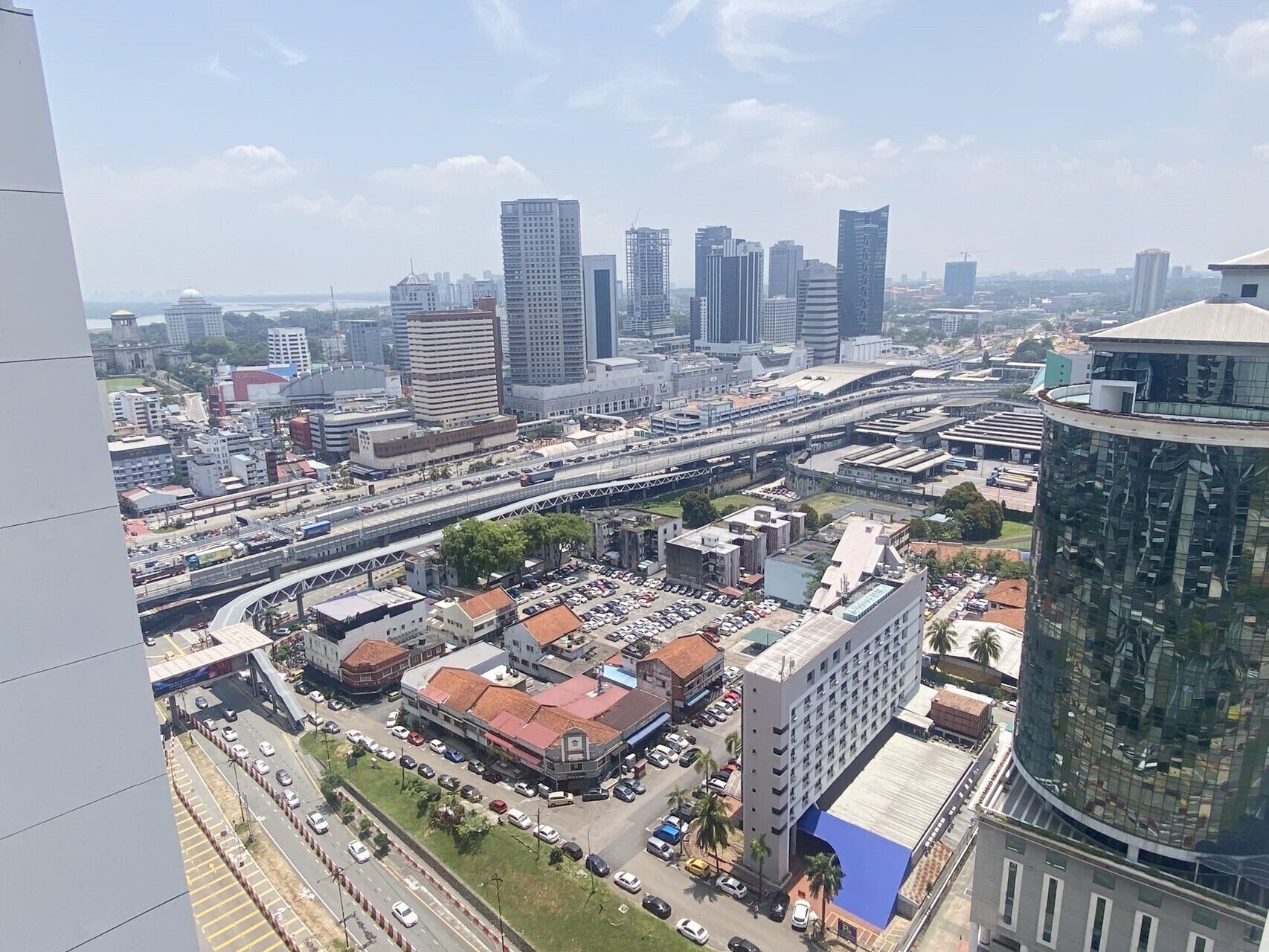 A cityscape with modern high-rise buildings, a busy highway, and a parking lot.