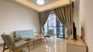A modern living room with a sofa, chairs, a coffee table, and a TV on a wooden stand. - R&F TrexHomestay (Johor Bahru)