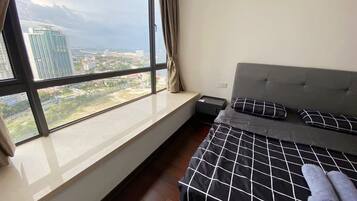 A bedroom with a large window, a bed with a black and white checkered bedspread, and a grey headboard.