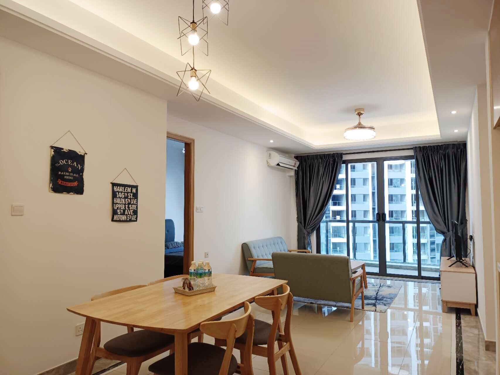 A modern living room with a dining area, a sofa, and a large window with curtains.