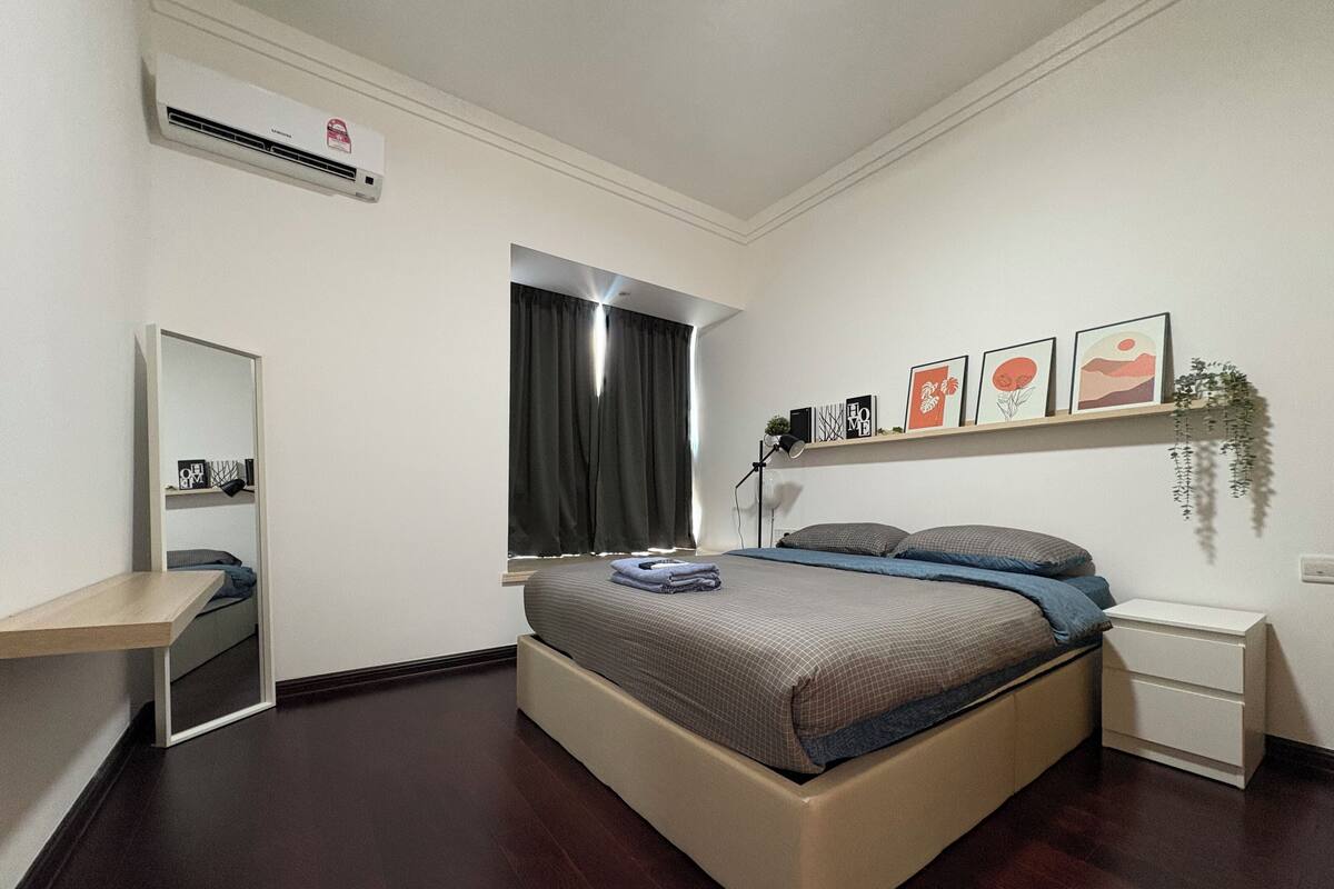 Une chambre à coucher comprenant un lit, des tables de chevet, un miroir, une fenêtre avec des rideaux et des étagères murales décorées de tableaux.