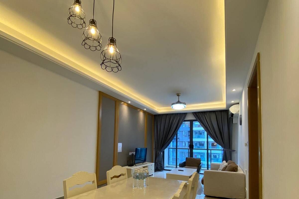 Un salon moderne avec un coin repas, comprenant une grande table, des sièges confortables et une vue sur la ville grâce à de grandes fenêtres.