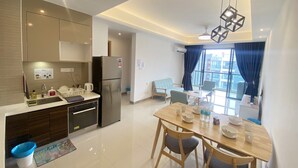 A modern kitchen with a refrigerator, sink, and dining area with a table and chairs. - R&F TrexHomestay (Johor Bahru)