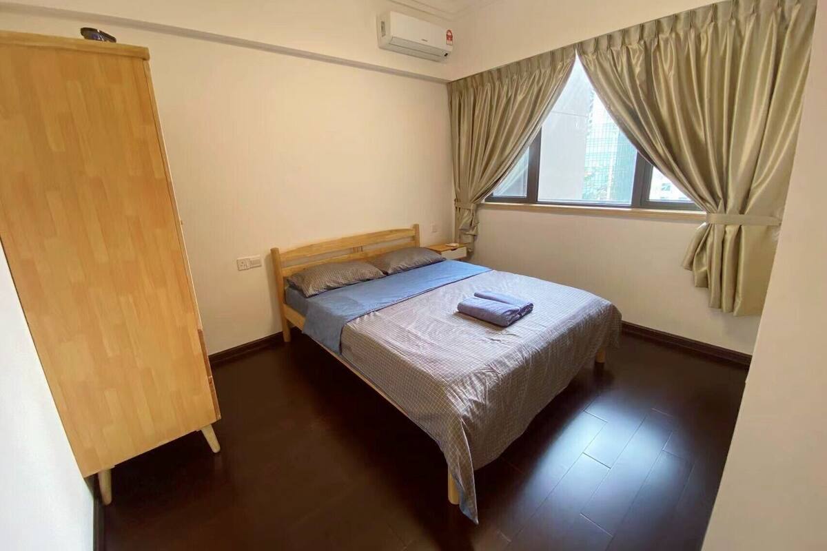 Une petite pièce propre, avec un lit simple, une armoire et une fenêtre avec des rideaux.
