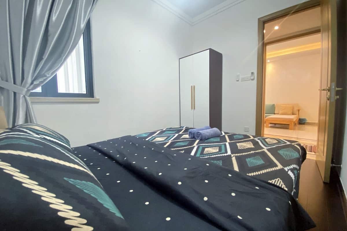 Une chambre à coucher comprenant un lit, une armoire et une porte donnant sur une autre pièce.