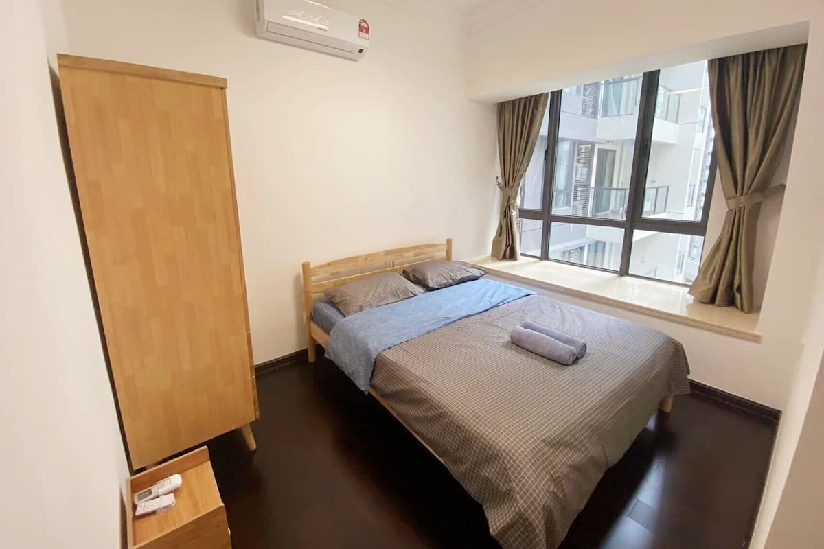 Une chambre à coucher comprenant un lit, une armoire, une fenêtre avec des rideaux et un appareil de climatisation.