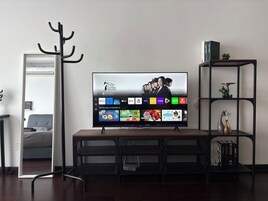 A television mounted on a wall with a selection of streaming services displayed.