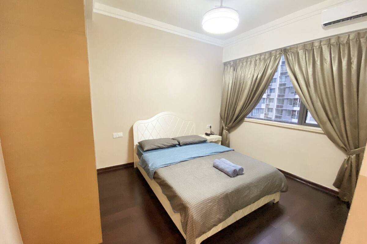 Une chambre à coucher avec un lit, des rideaux, une fenêtre et un appareil de climatisation.